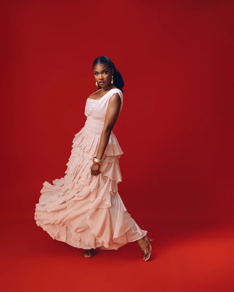 The Bloom gown in pale blush, moving across a red studio set.